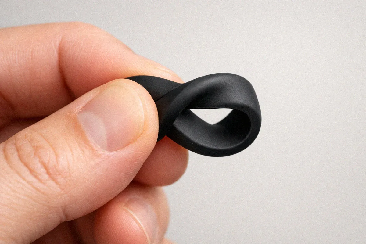 Hand pinching and twisting a black silicone ring to test for filler content with no white stress marks appearing
