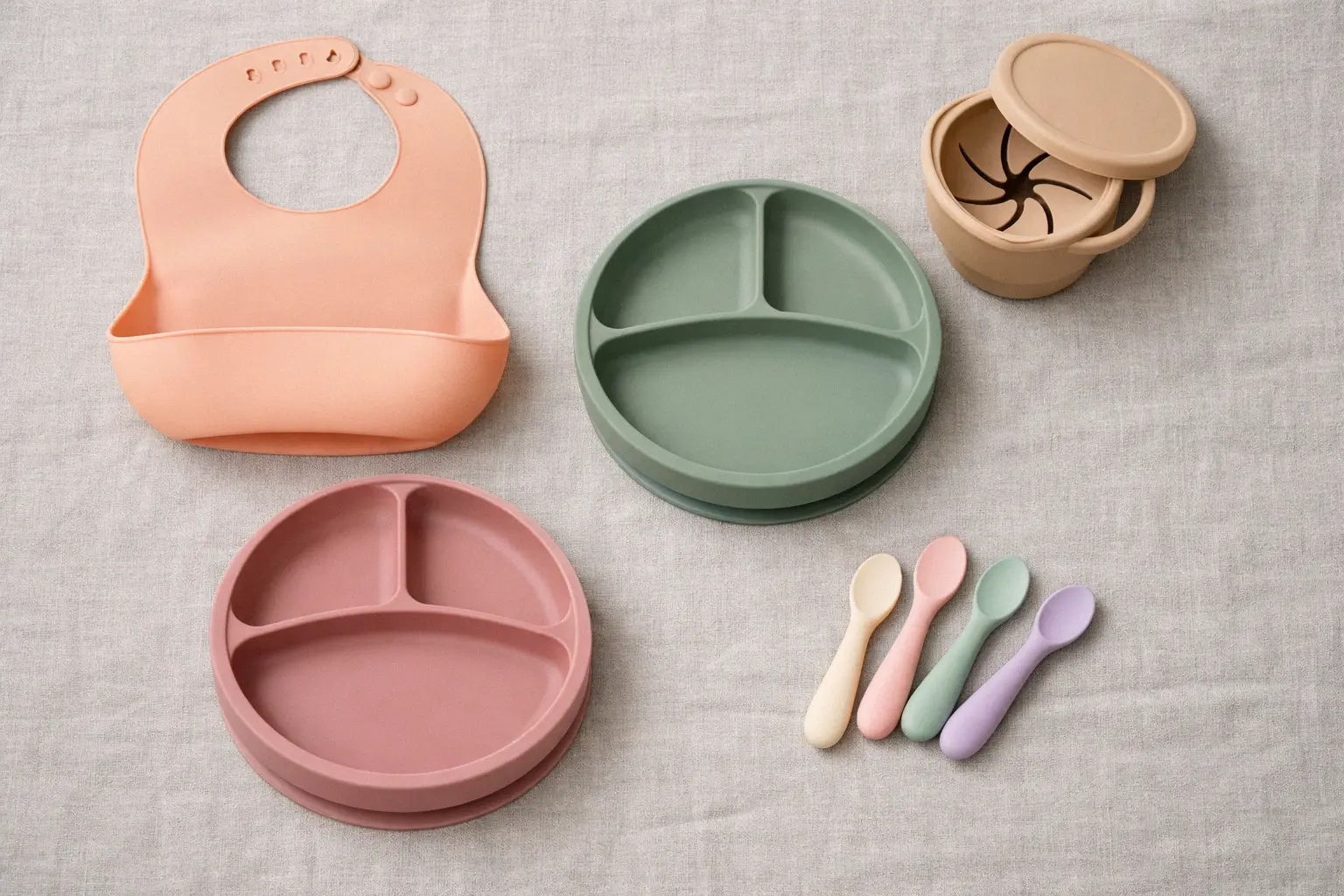 Silicone baby feeding products including bibs plates spoons and food storage containers in soft pastel colors