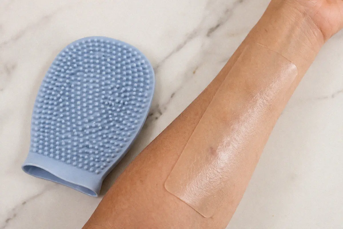 Silicone body care products including exfoliating mitt and silicone scar treatment sheet on skin