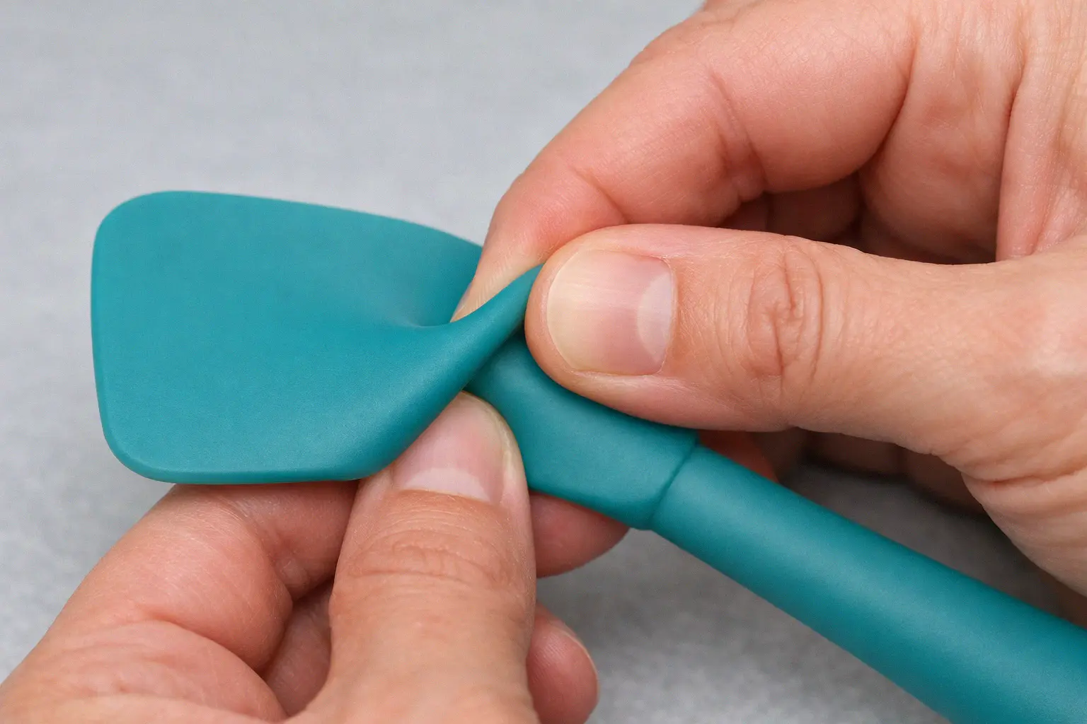 Performing the pinch test on a silicone kitchen spatula to verify food grade purity with no filler marks