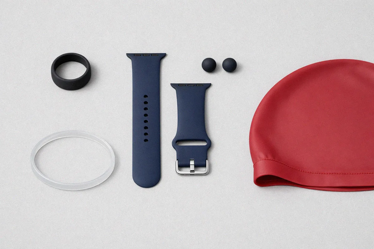 Collection of silicone wearables including rings watch bands bracelets earrings and a swim cap laid out on a neutral background